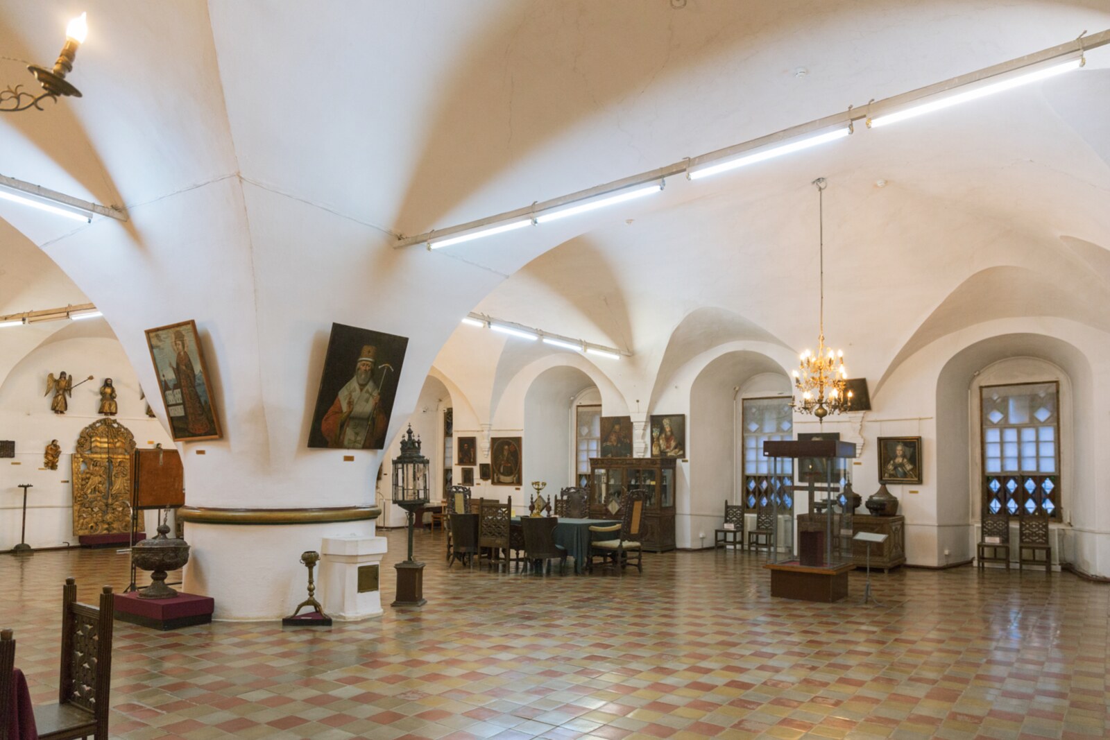 The light vaulted hall of the White Chamber, with one central pillar and museum objects.