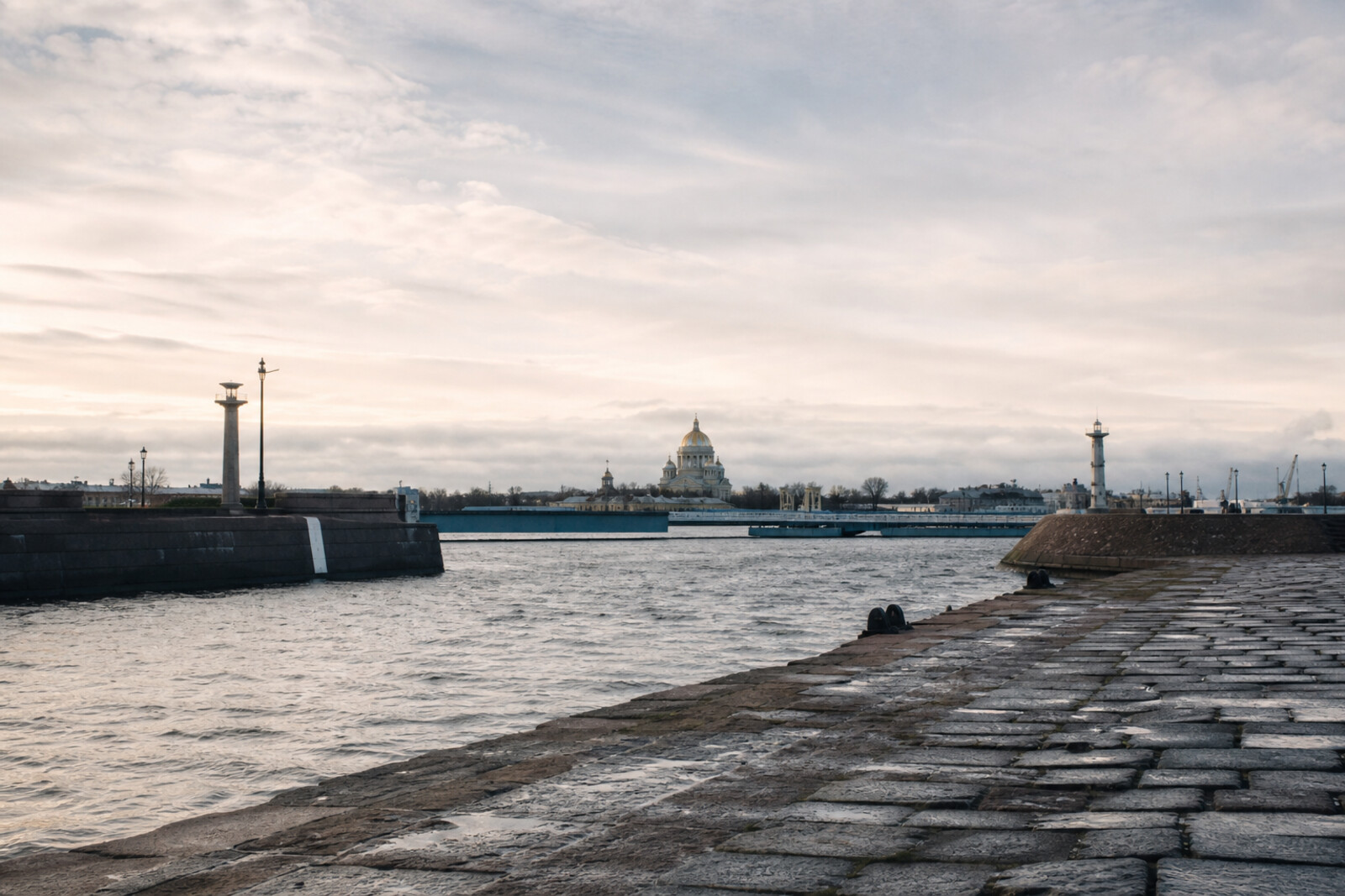The Naval Cathedral of St Nicholas beyond the granite line of the dock and an anchor, with the low silhouettes of Kronstadt forts on the horizon.