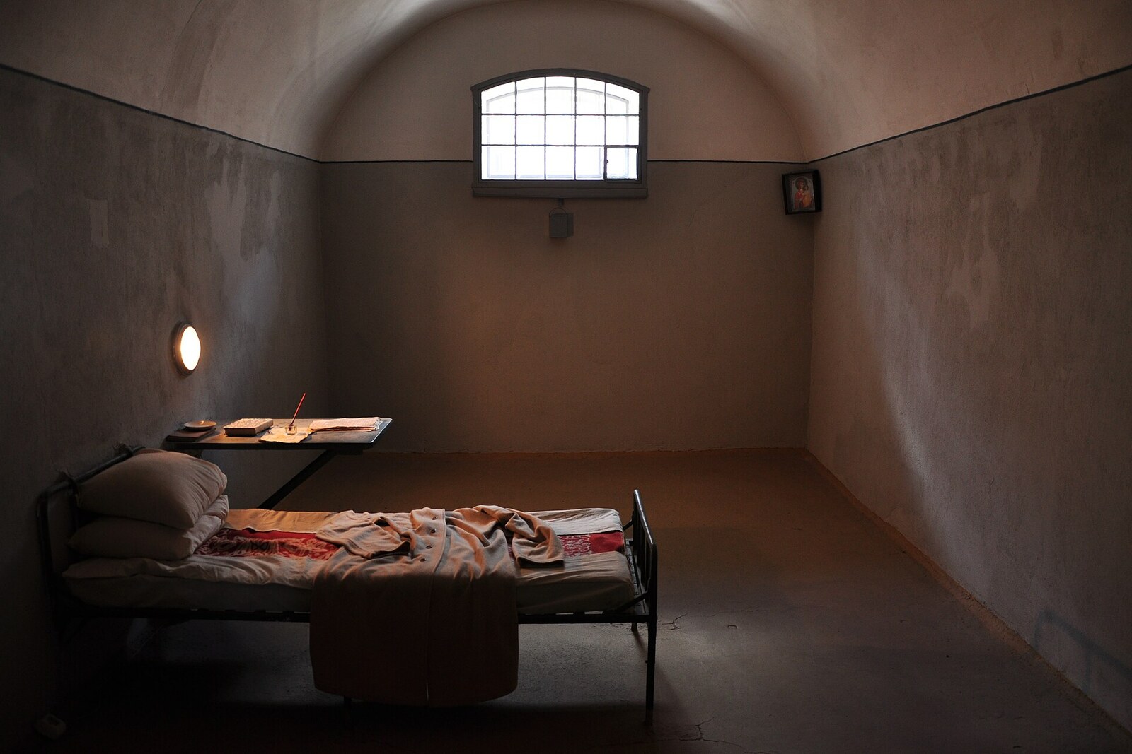 A solitary cell with a cot and a small window in Trubetskoy Bastion.