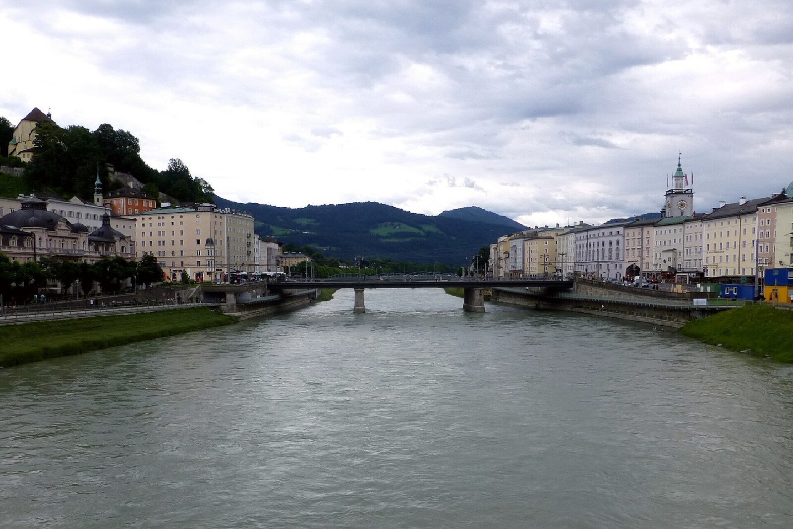 A modern steel bridge with pedestrians and a view of the city across the river