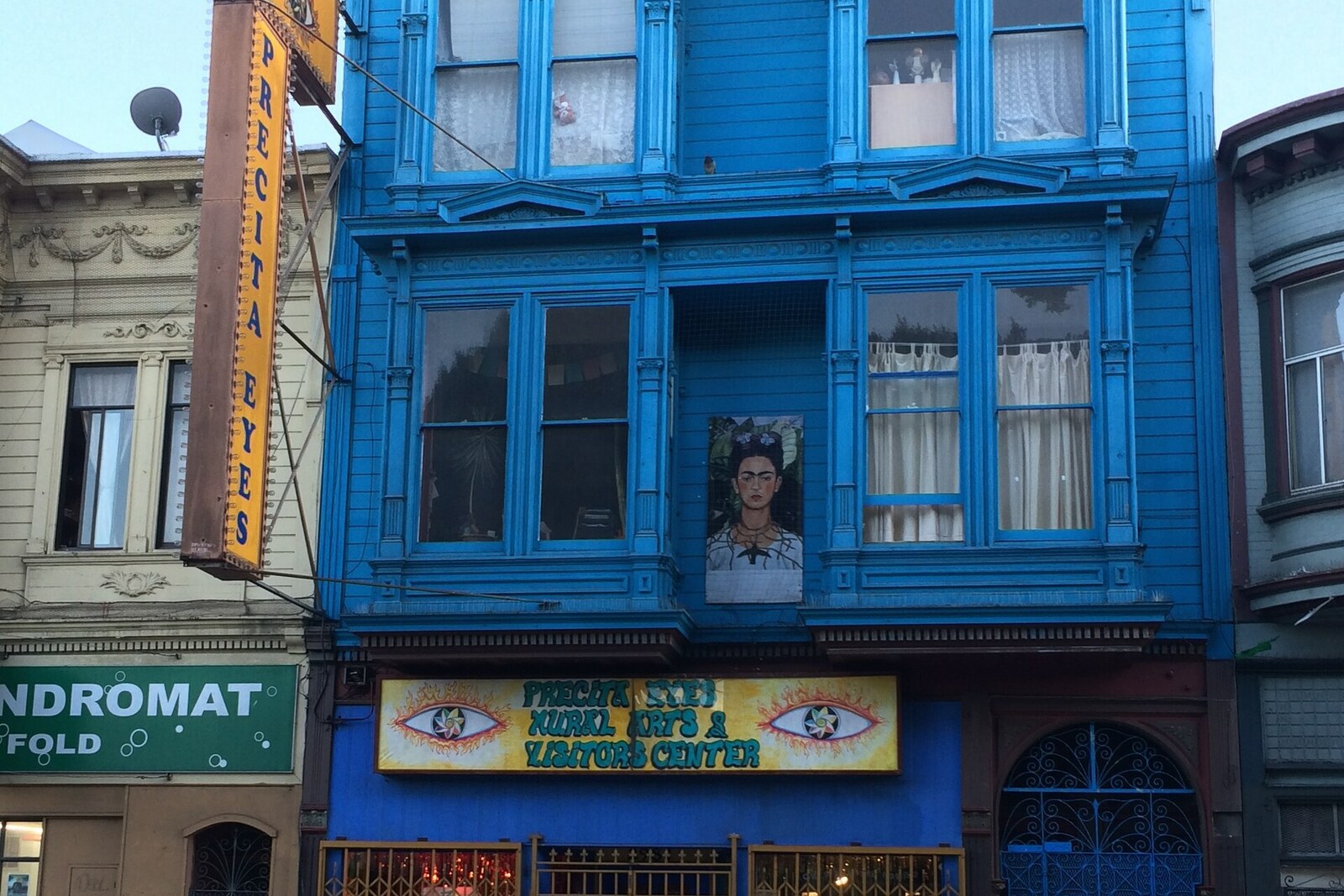 The blue upper facade of the Precita Eyes Center and its vertical sign.
