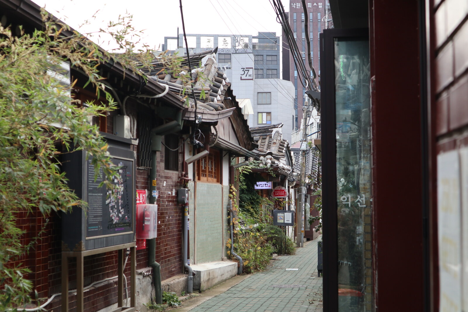 A narrow alley in Ikseon-dong with hanok roofs and modern façades.