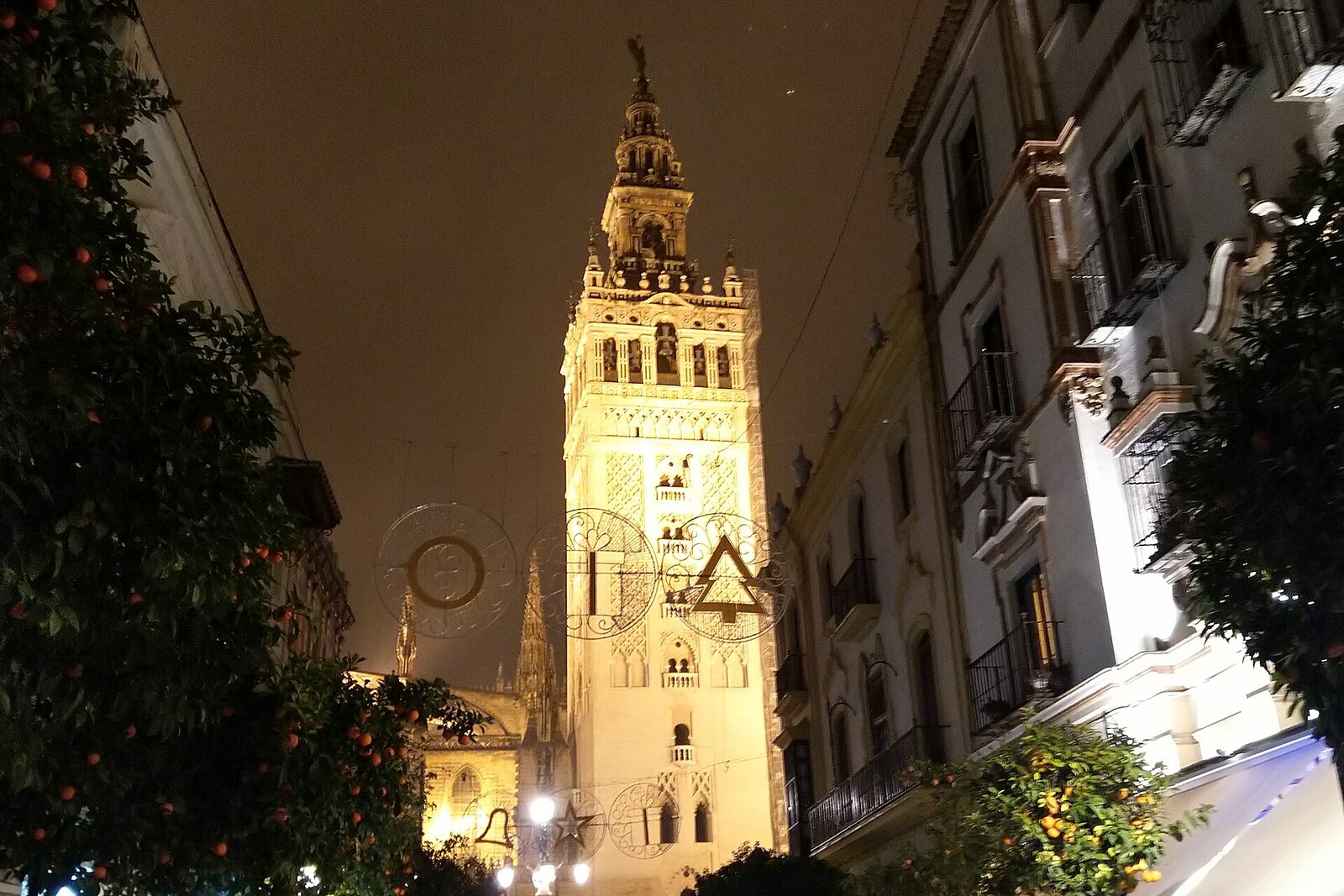 Calle Mateos Gago with a view of the Giralda bell tower, terraces, and people seated at bars.