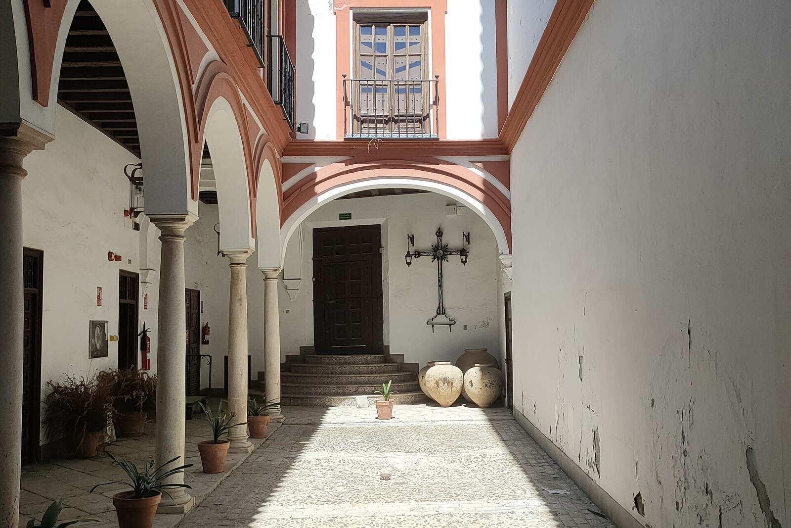 Facade of Hospital de los Venerables with an arched entrance and a striped roof.
