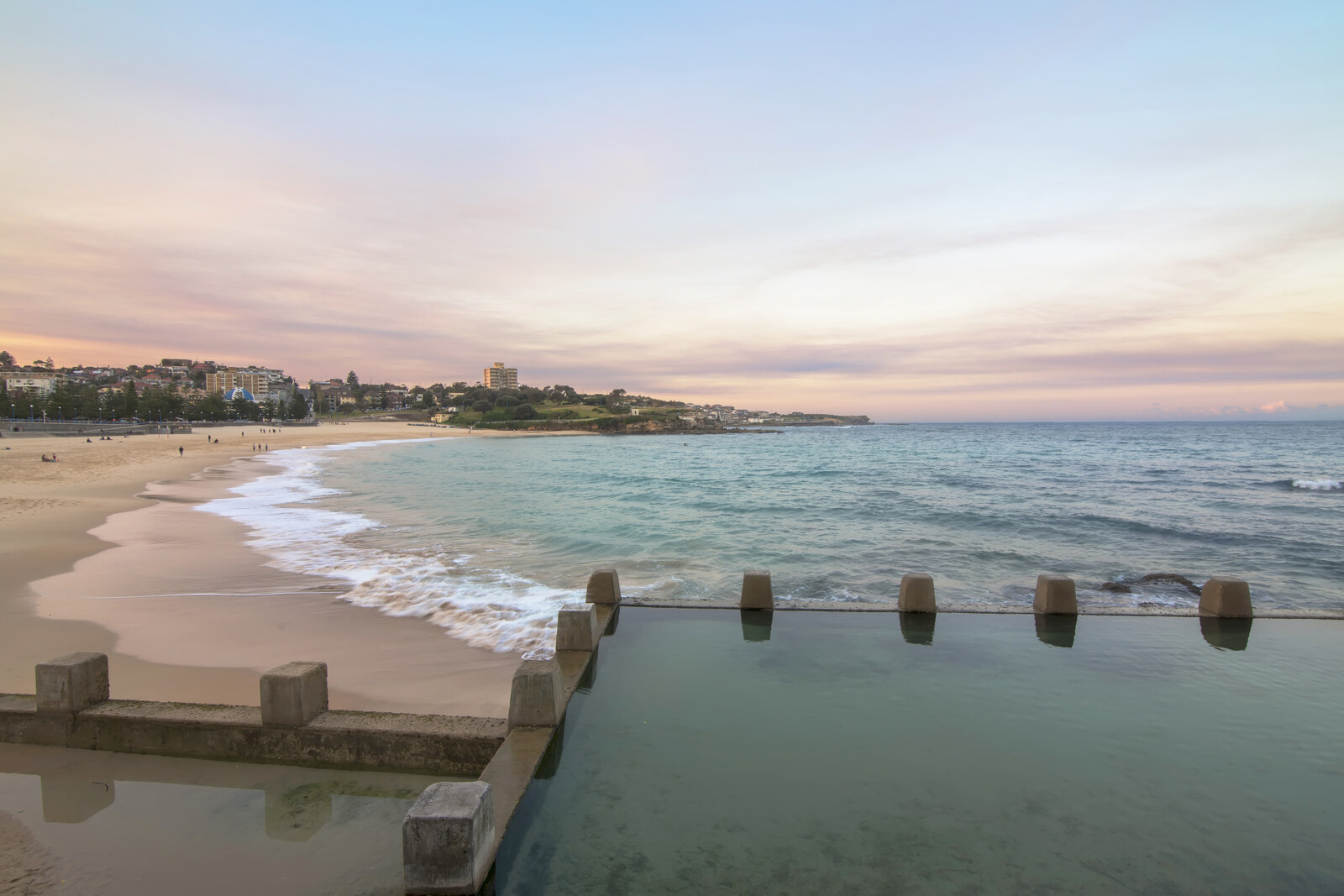 Coogee Beach with a stone pool and a strip of sand under bright sunshine