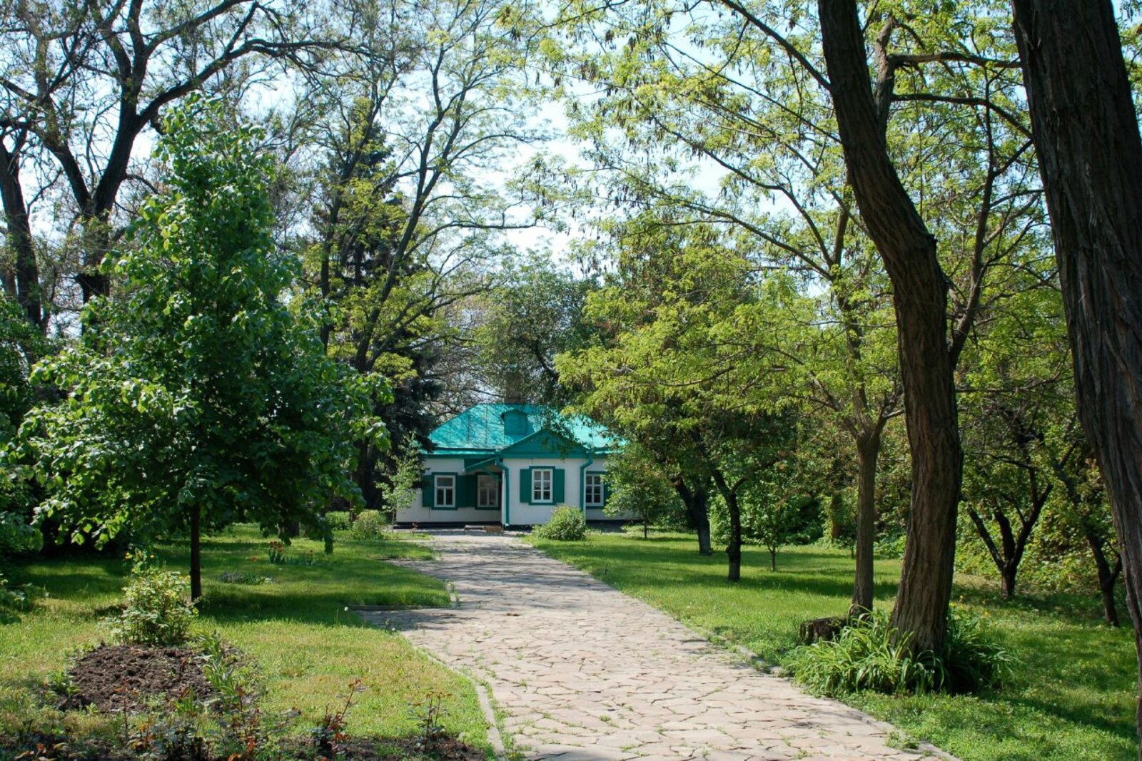 Chekhov's small white birthplace house beneath a green roof in a courtyard.
