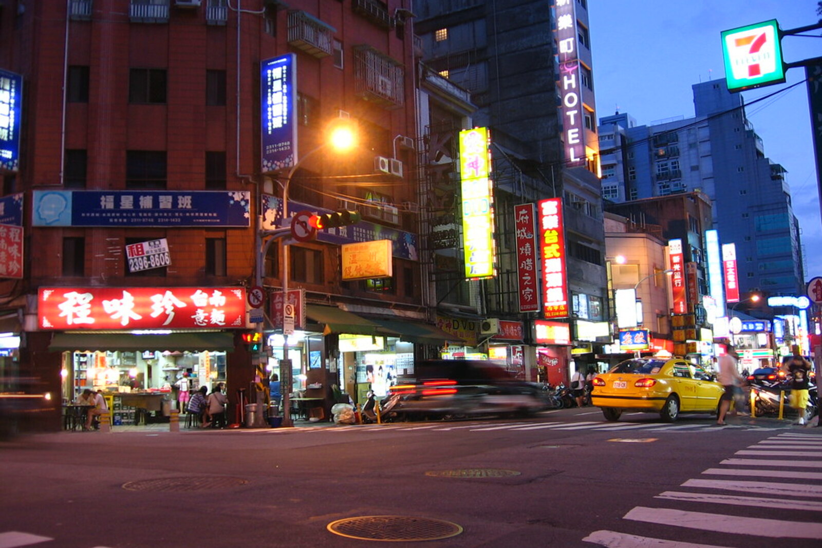 Ximending pedestrian zone in the evening, with street signs and urban crowds.