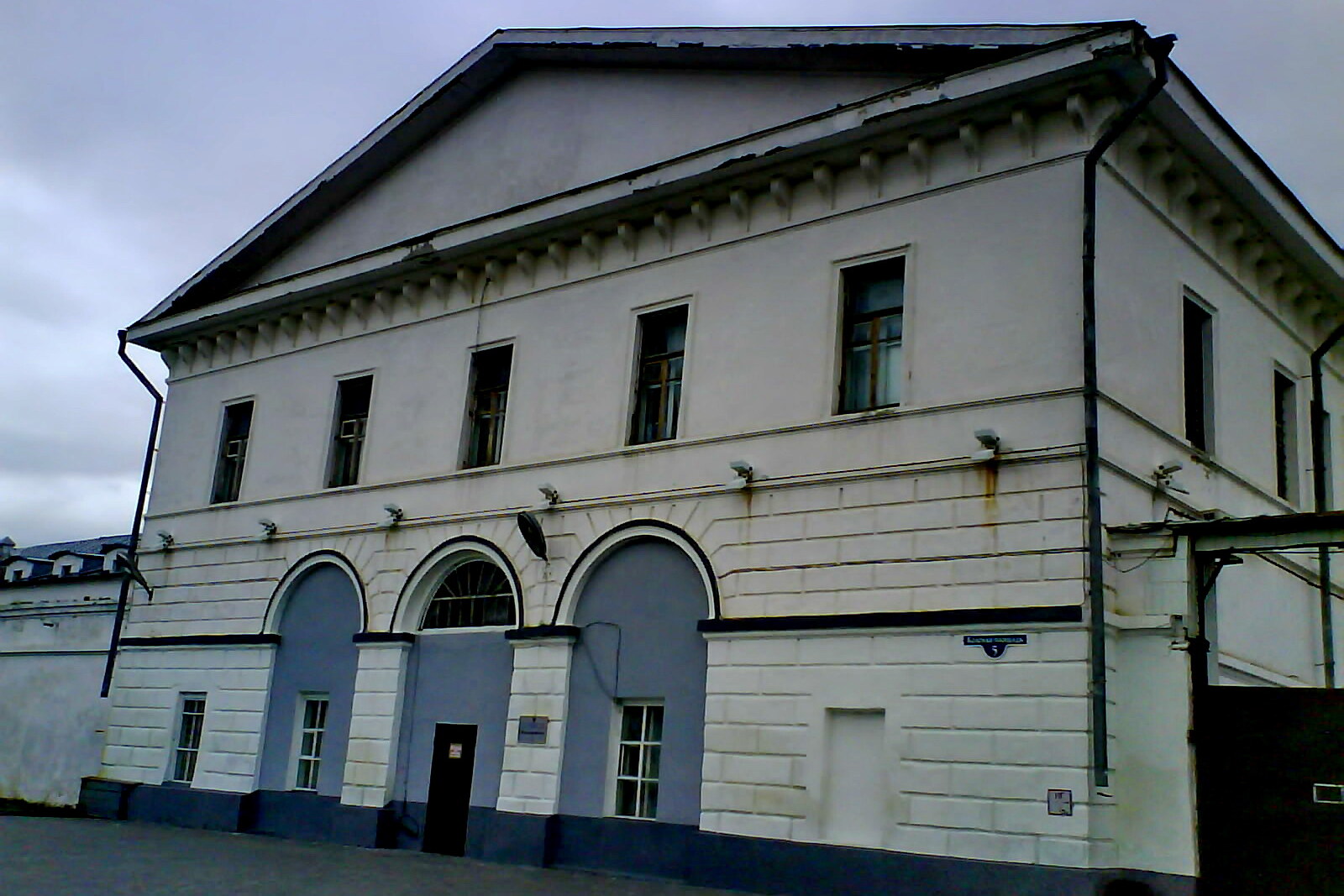 The pale building of Tobolsk Prison Castle behind a fence.