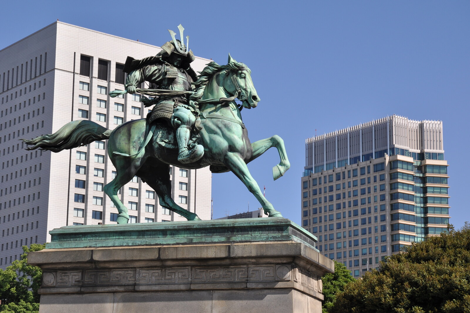 A bronze samurai on a galloping horse against a blue sky