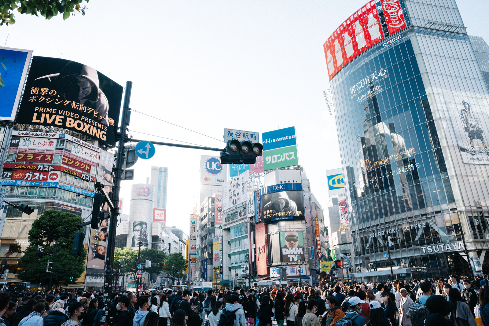 Shibuya Crossing with crowds of pedestrians and neon screens