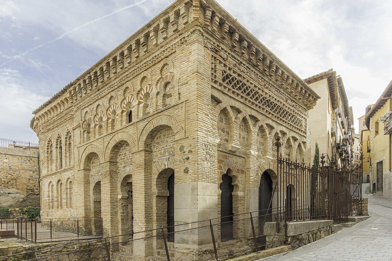 The brick façade of Cristo de la Luz with arches and a Kufic frieze.