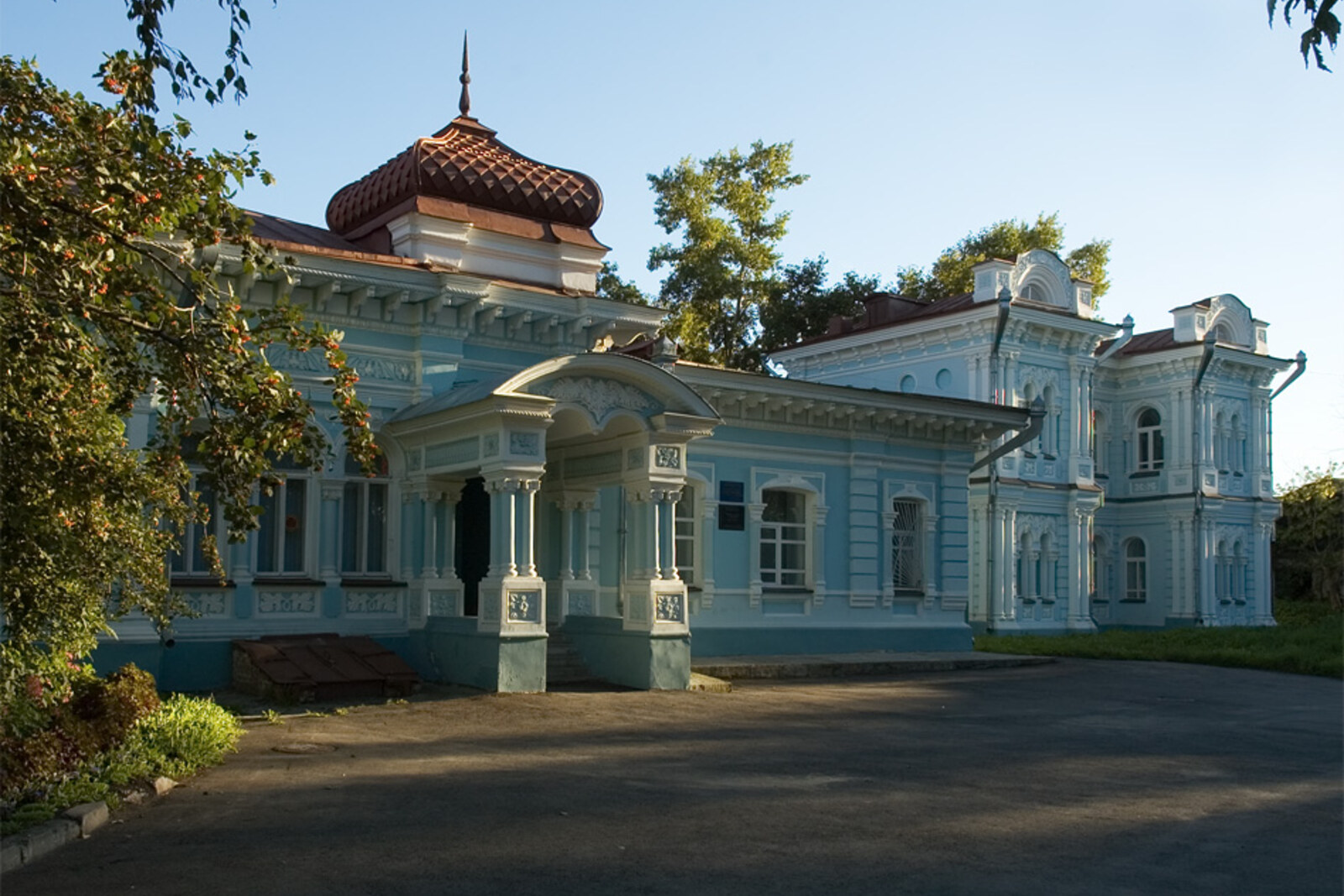 The blue wooden Karim-bai House with a turret and a carved porch.