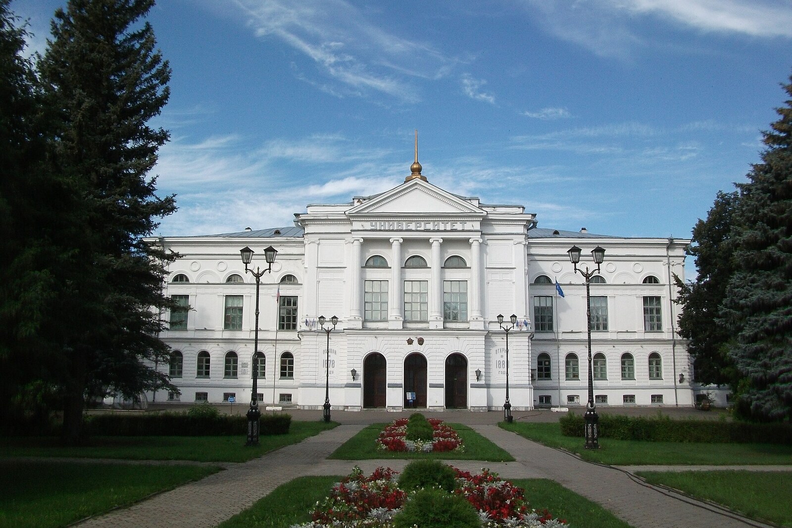 The white Main Building of Tomsk State University behind a fence.