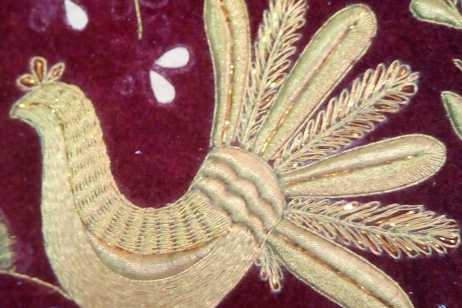 Close-up of gold embroidery with metallic threads and holding stitches.
