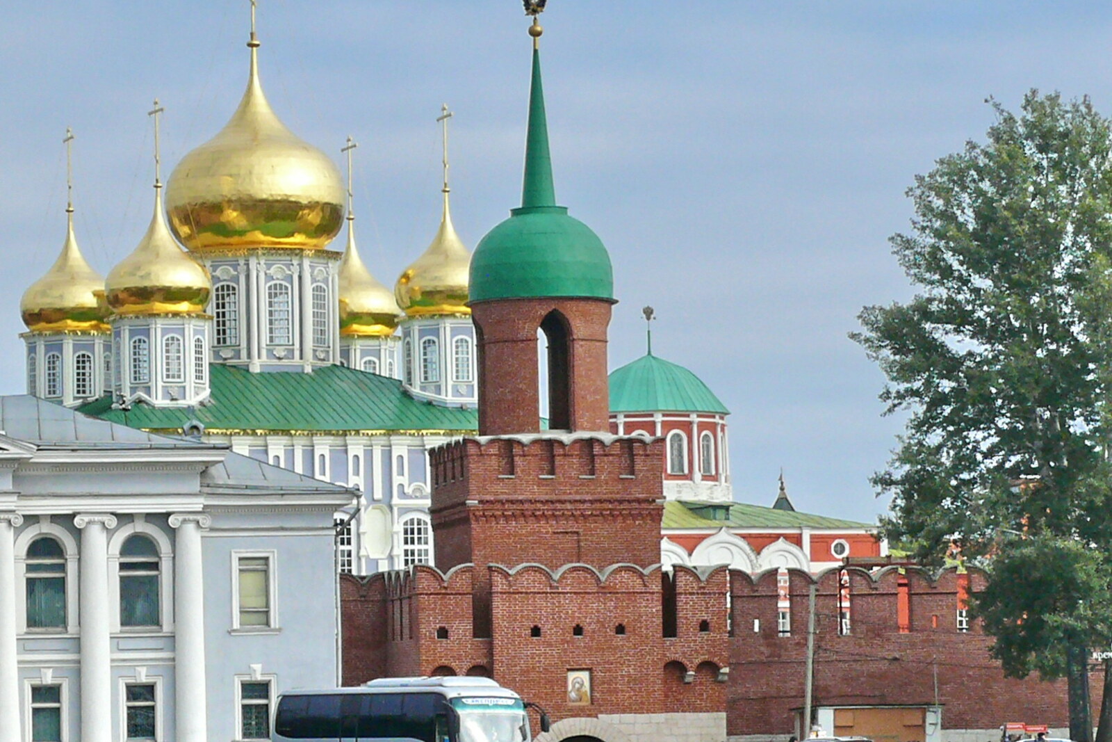The red-brick Odoev Tower with a green dome and spire against the backdrop of the Kremlin cathedral.