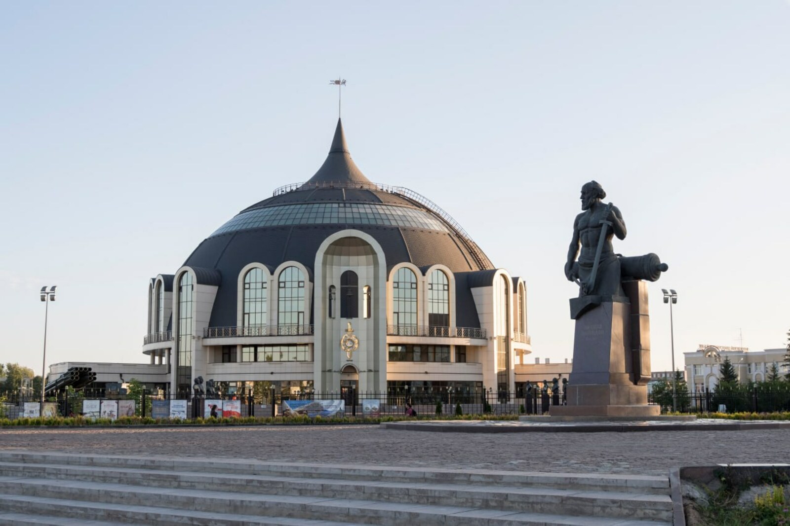 The domed, helmet-shaped building of the Tula State Museum of Weapons and the monument to Nikita Demidov in front of it.