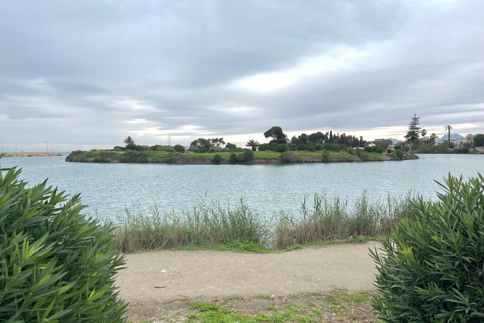 The circular basin of the Punic Ports, reflecting the sky and surrounded by ruins.