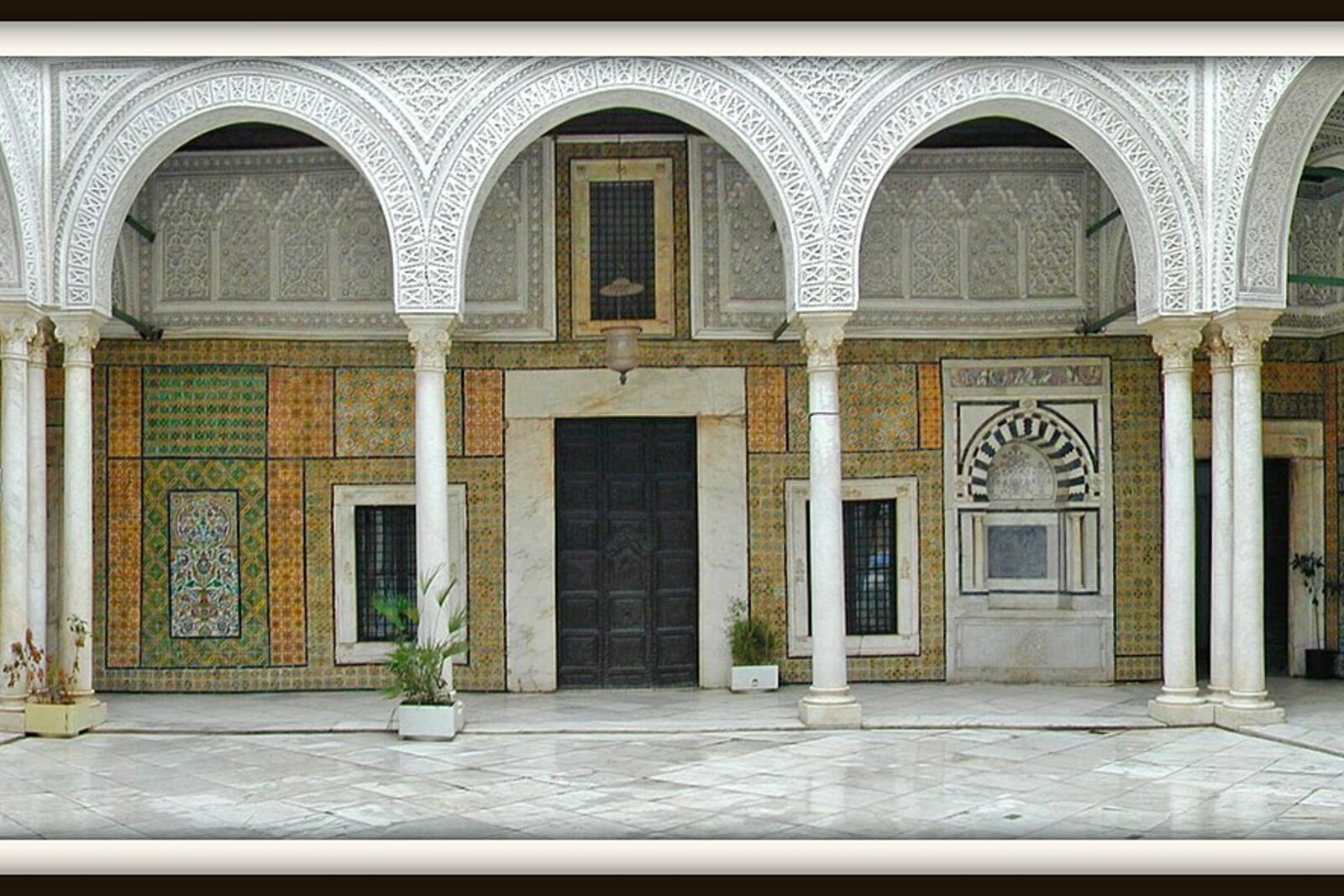 The marble courtyard of Dar Hussein, with arches and ceramic panels.