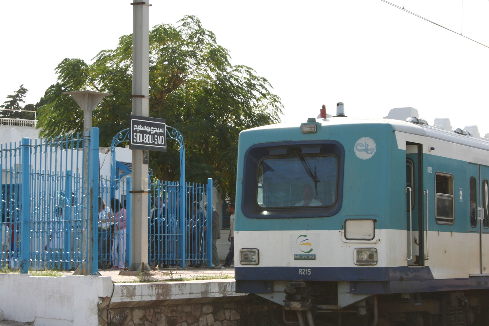 A suburban-line train at Sidi Bou Said Station, with a blue fence and station sign.
