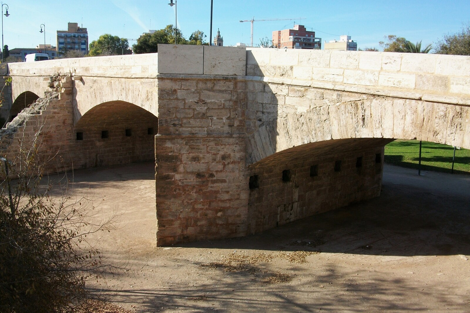 Serranos Bridge of stone above the green bed of the Turia River