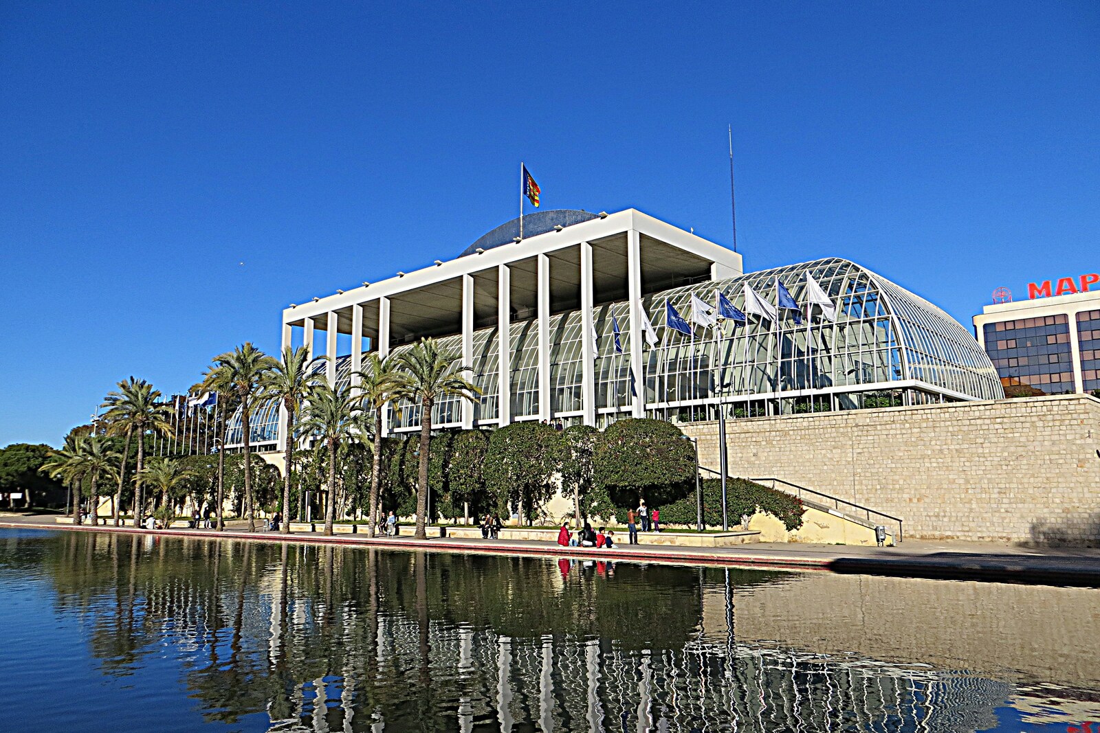 The glass façade of Palau de la Música reflected in a pond