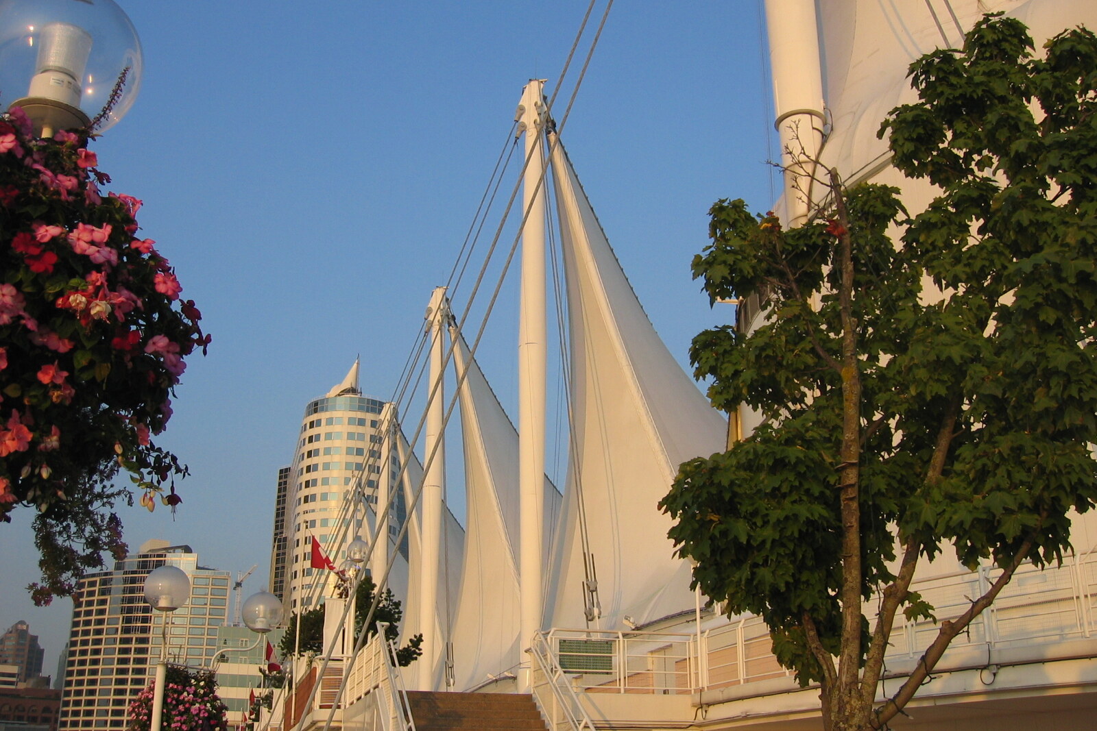 The white sails of Canada Place and a pier in Vancouver against a blue sky.