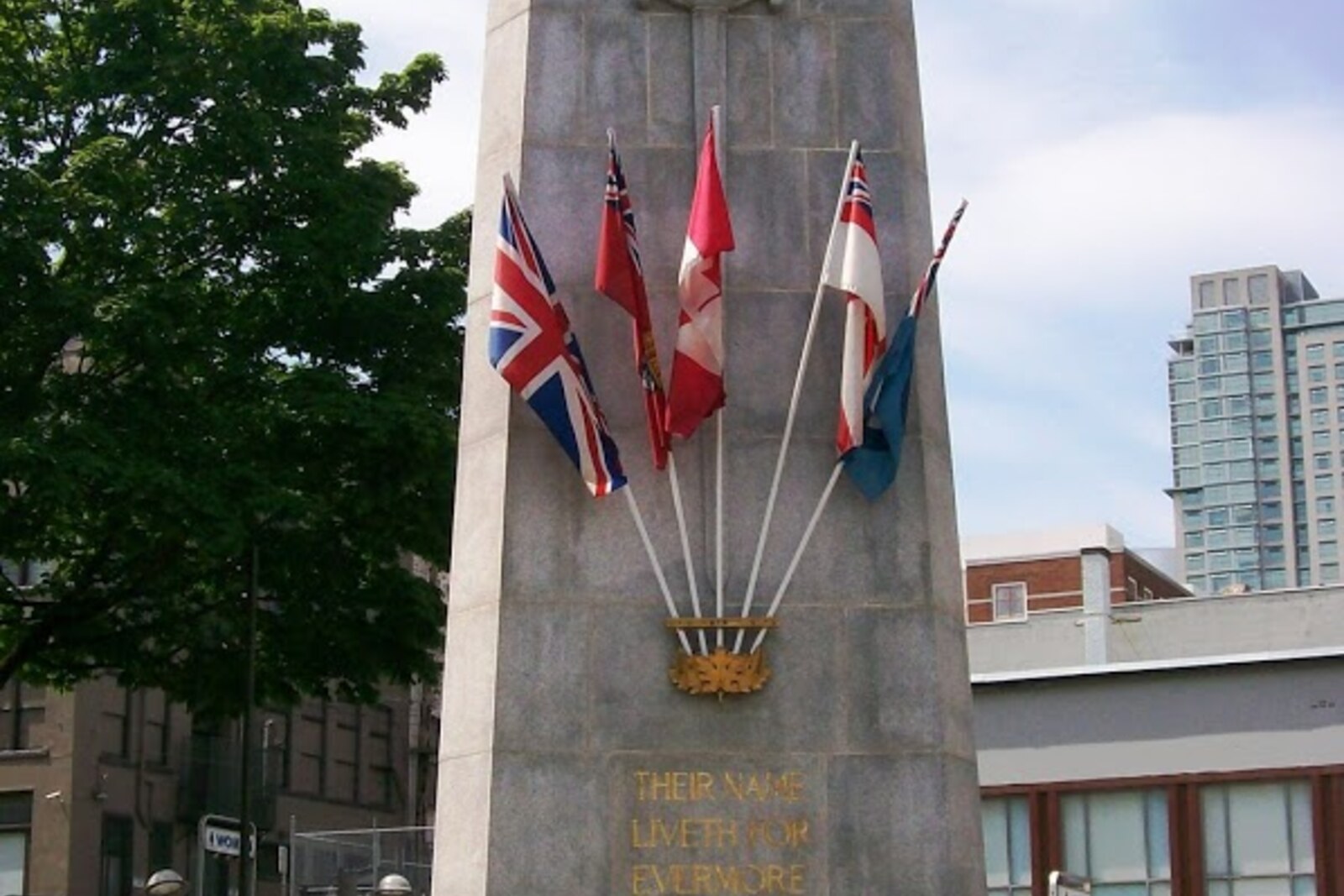 A granite obelisk—a memorial cenotaph in Victory Square, Vancouver—surrounded by trees.