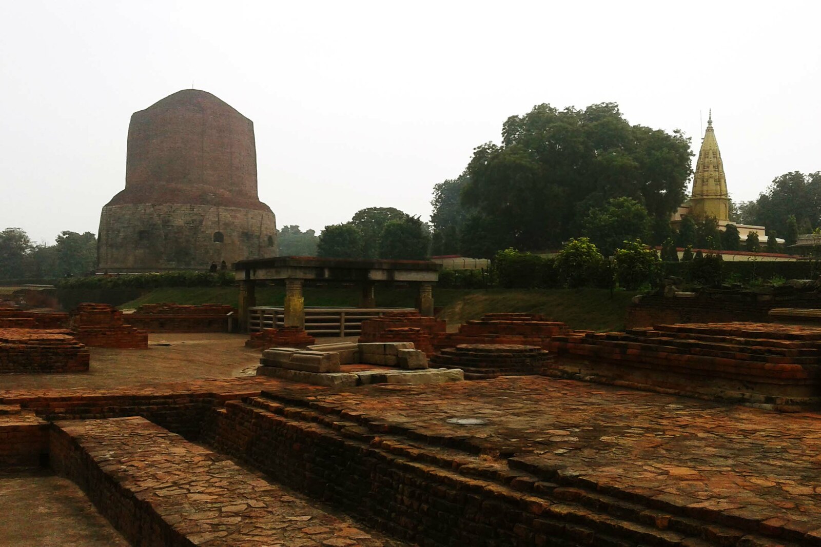 The archaeological area of Sarnath with brick ruins and the Dhamekh Stupa.