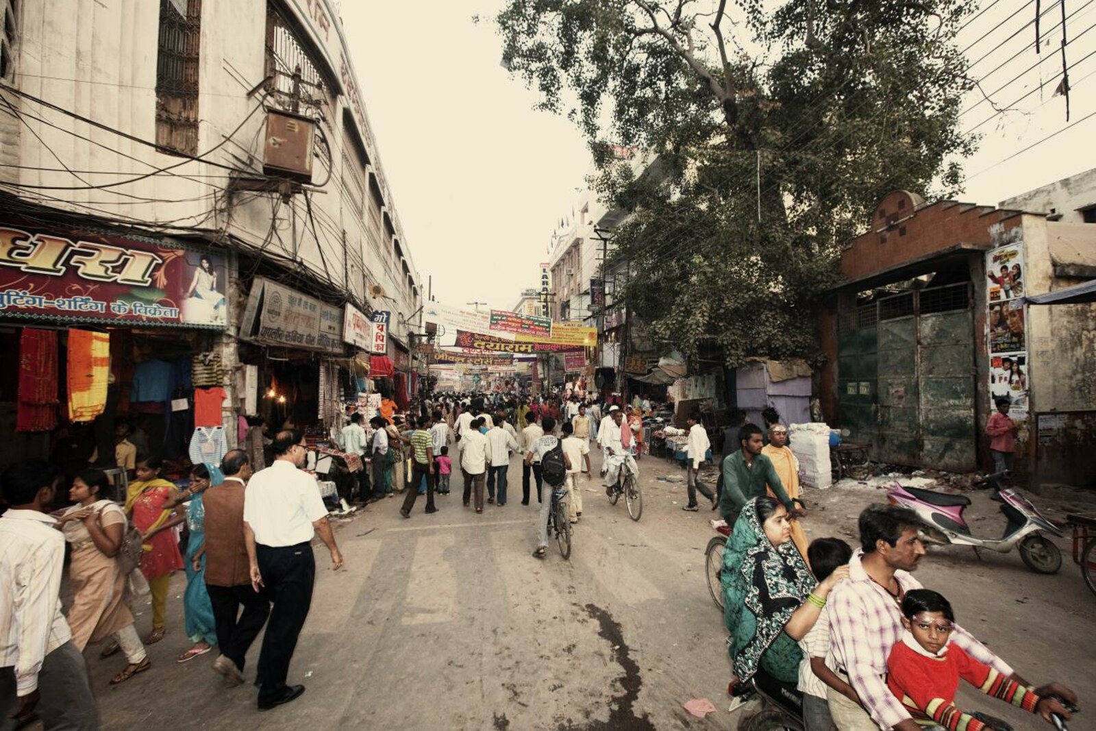 Narrow roads and shops at the Godowlia intersection, with many people and rickshaws