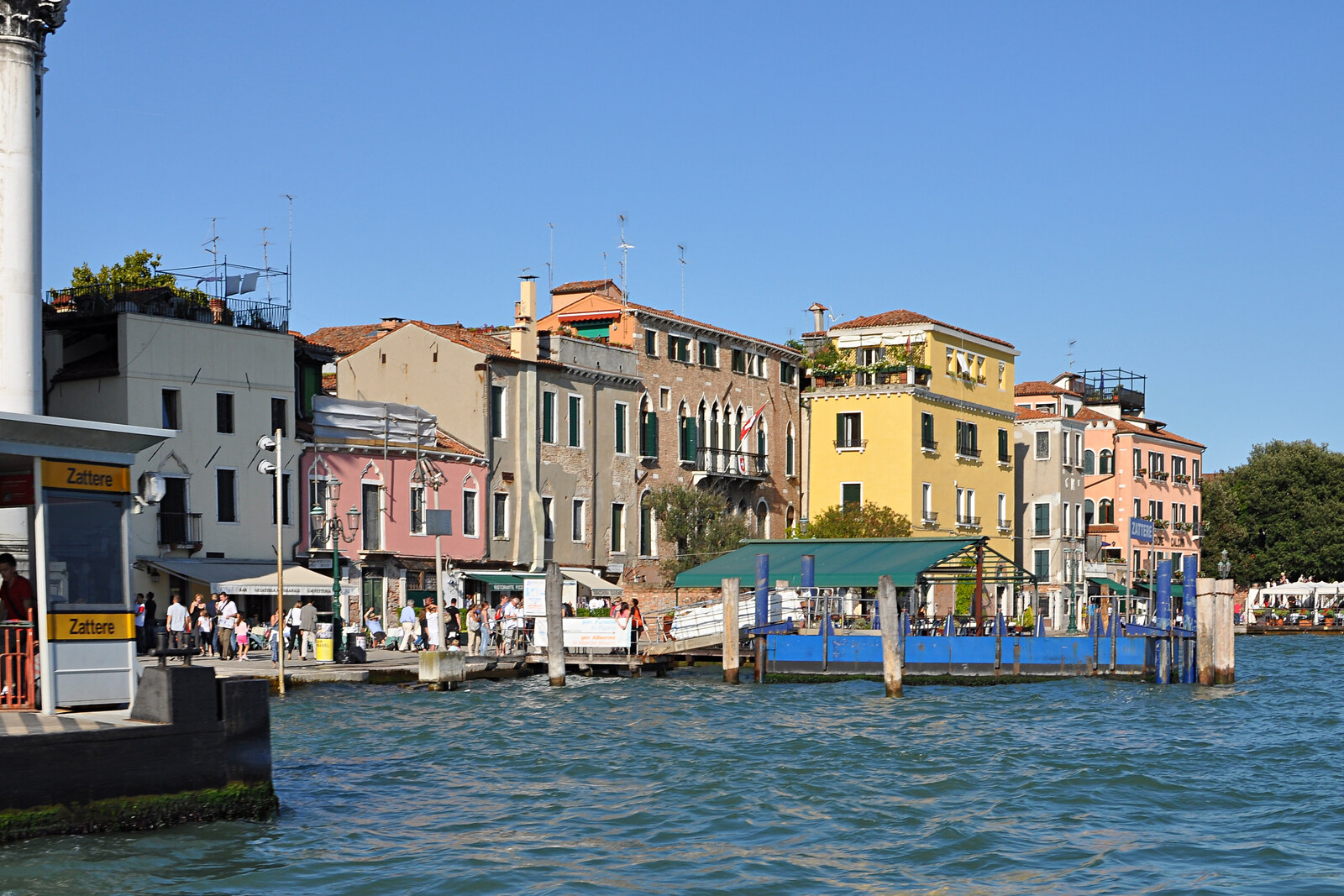 A sunny Zattere waterfront with houses reflected in the water and the island of Giudecca opposite.