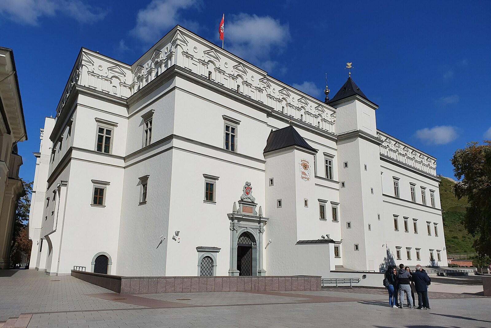 The light-colored restored facade of the Palace of the Grand Dukes of Lithuania under a blue sky.
