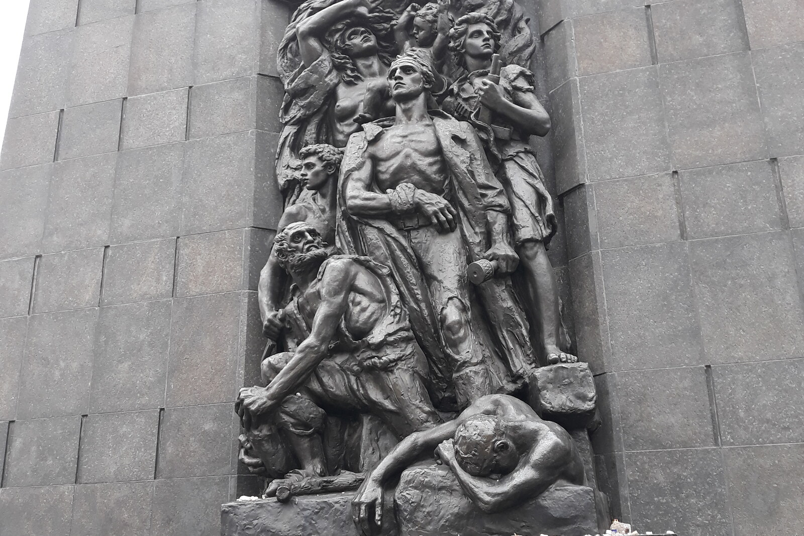 Bronze figures of fighters on the dark wall of the Monument to the Ghetto Heroes in Warsaw.