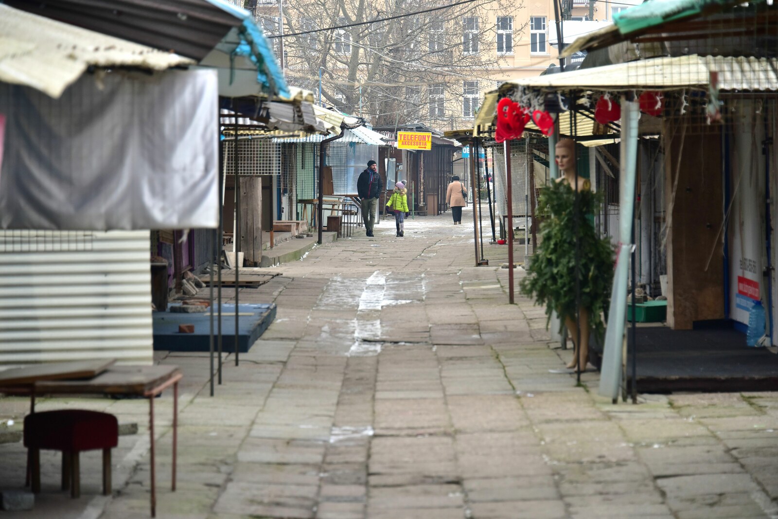 The gates of Różycki Bazaar and a row of stalls with shoppers