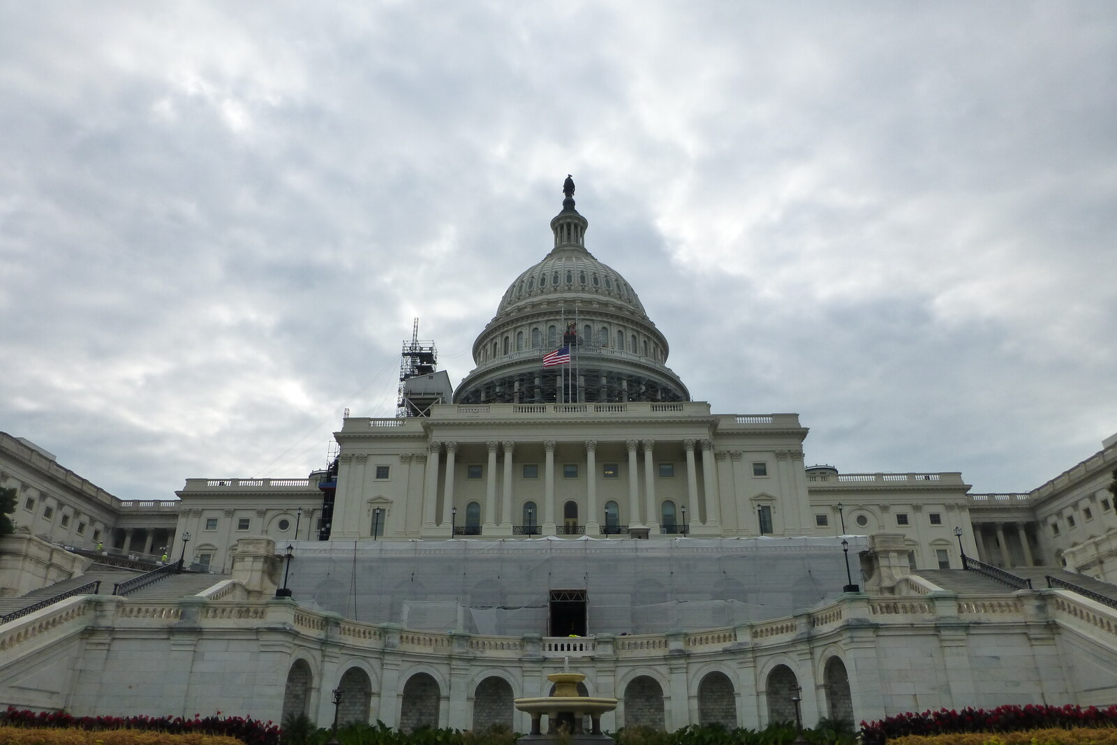 A fountain in front of the U.S. Capitol is surrounded by green lawns.