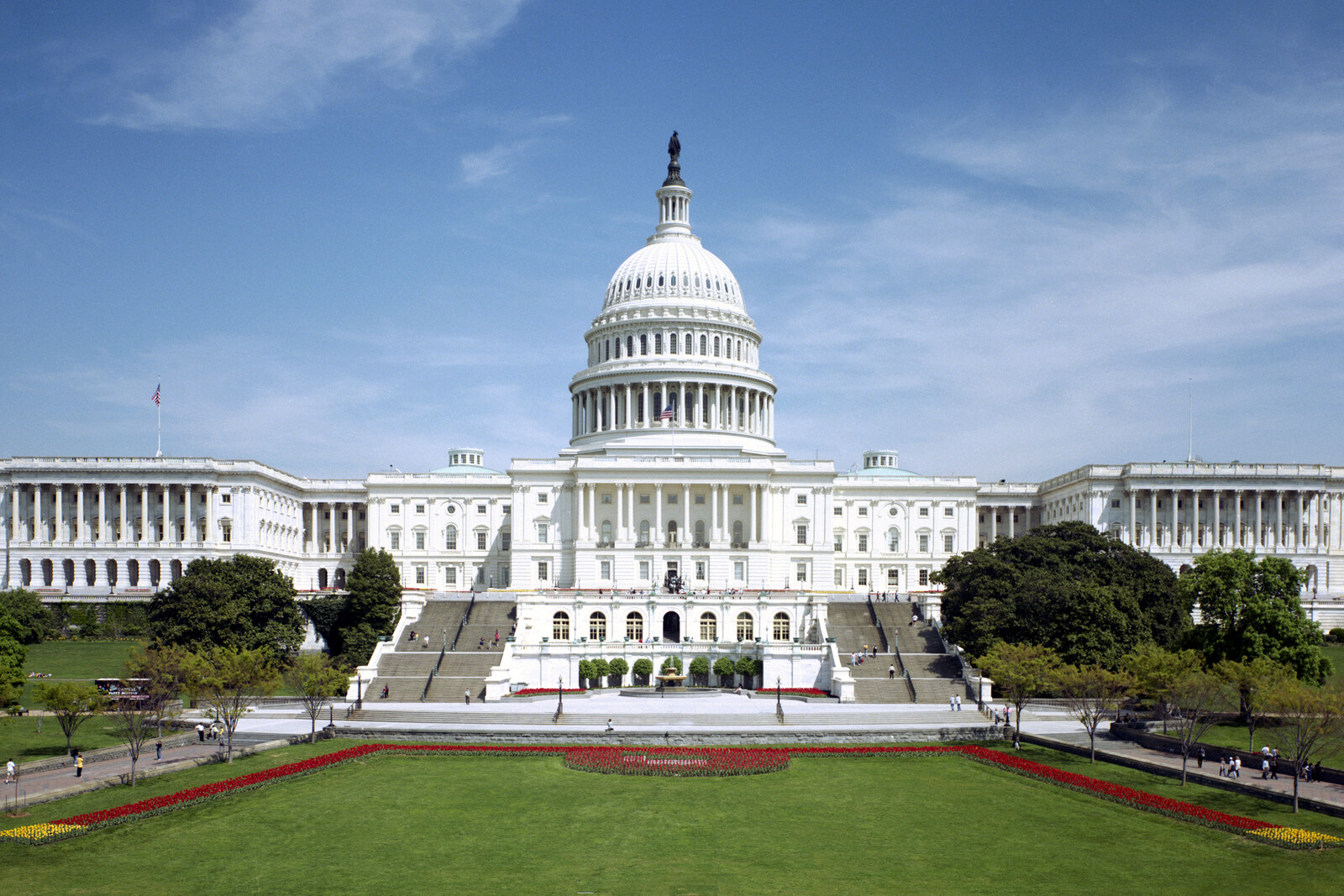 White dome and west facade of the Congress building under a blue sky.