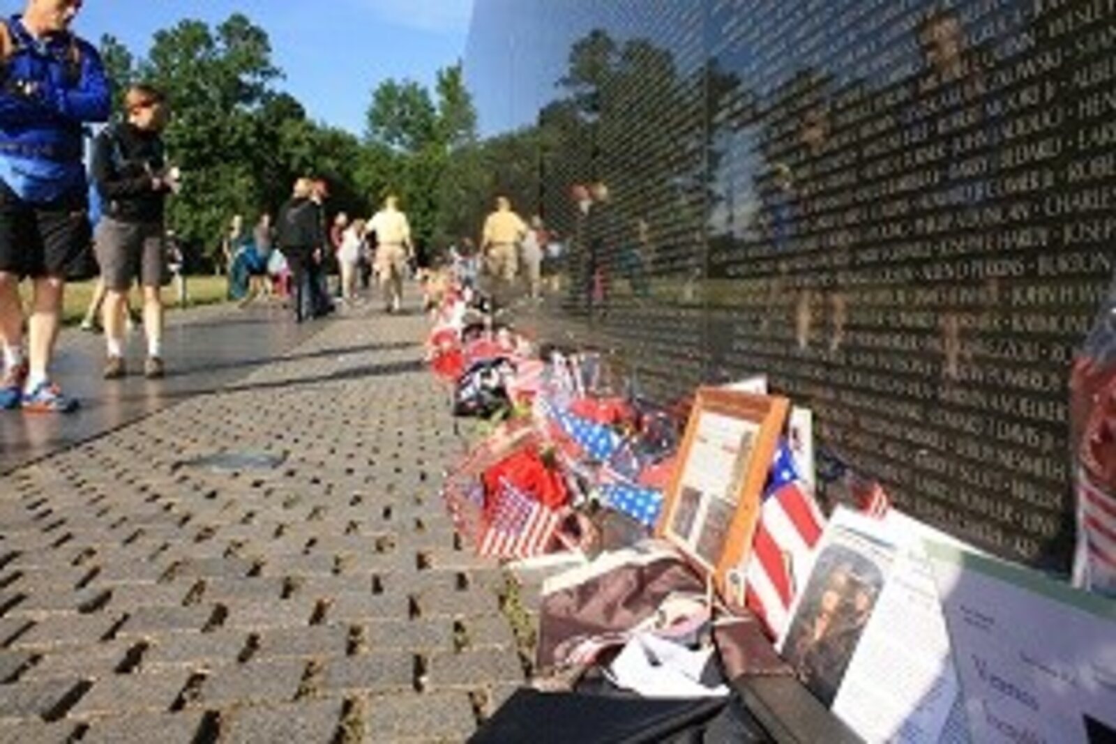 The wall of the Vietnam Veterans Memorial with a reflection and a flag.