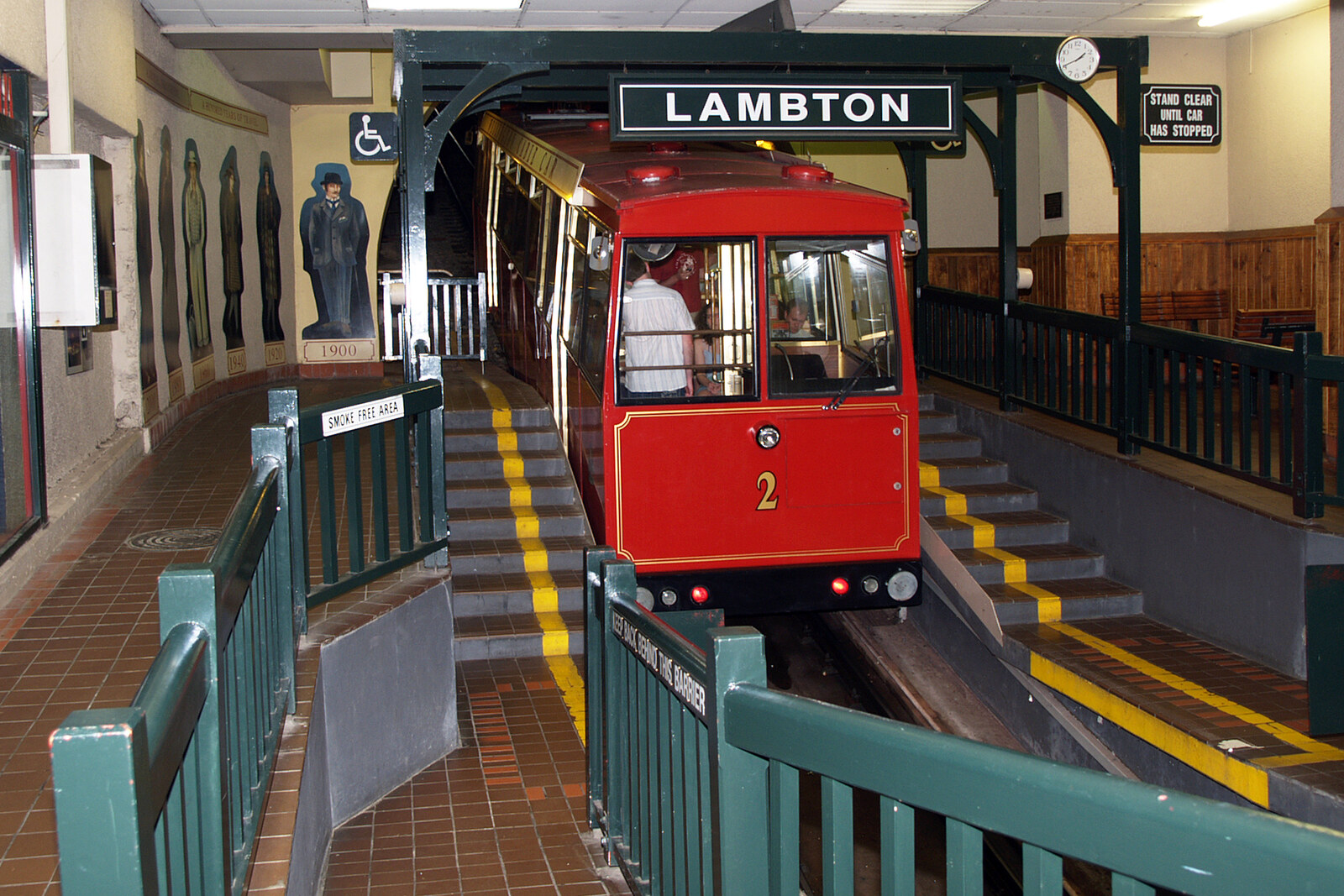 A Wellington Cable Car pulls into the upper station against a cityscape.