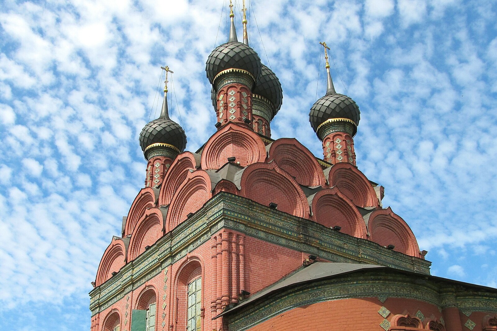 Red Church of the Epiphany with five dark domes and bands of colorful tiles.