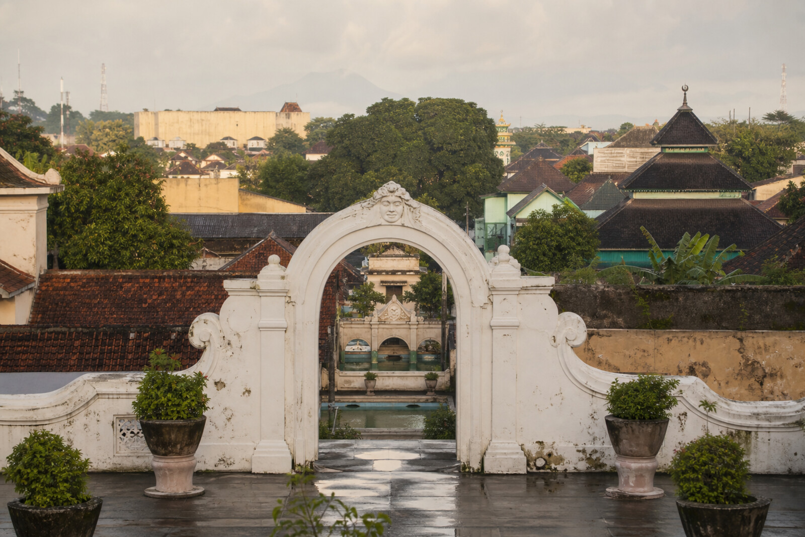 A stylized Yogyakarta axis from the southern gate through Taman Sari, a mosque, banyan trees, the market, and the fort toward the silhouette of Mount Merapi.