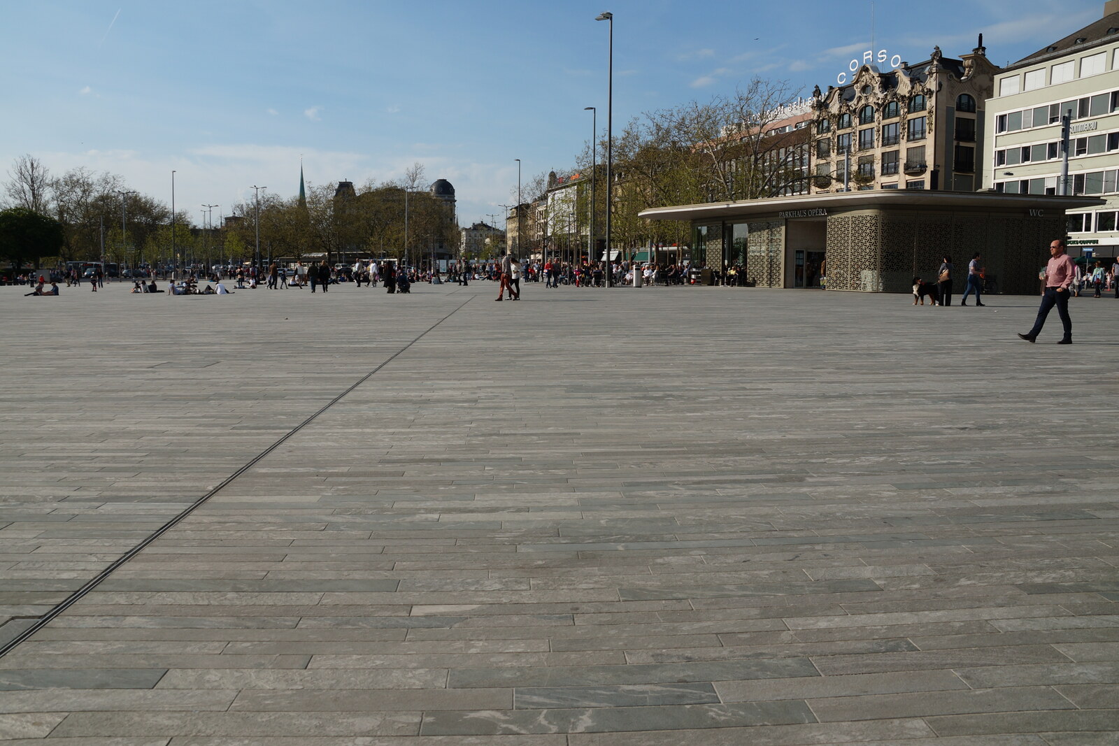 The open Sechseläutenplatz between the opera house and Bellevue, with stone paving and people.